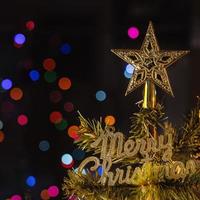 belo conceito de decoração de natal, bugiganga pendurada na árvore de natal com ponto de luz cintilante, fundo preto escuro embaçado, detalhe macro, close-up. foto