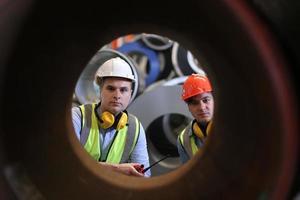 engenheiro industrial de homens usando um capacete de segurança em pé em uma fábrica industrial pesada. a manutenção procurando trabalhar em máquinas industriais e verificar a configuração do sistema de segurança na fábrica. foto