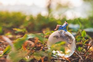 pessoas em miniatura tomando sol no globo de cristal no parque foto