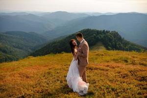casal de noivos apaixonados beijando e abraçando perto de rochas na bela paisagem foto