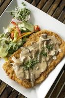 Costeleta de vitela alemã Jagerschnitzel schnitzel com molho de cogumelos e salada foto
