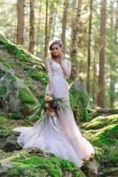 noiva feliz em um vestido de noiva rosa. a garota tem um buquê de casamento nas mãos dela. cerimônia de casamento estilo boho na floresta. foto