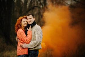 jovem casal feliz segurando bombas de fumaça no acampamento foto