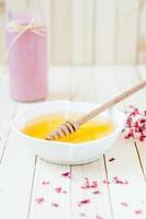 pote de mel amarelo na mesa rústica com smoothie de morango rosa foto