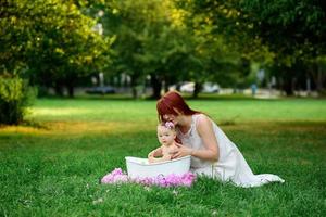 mãe ajuda sua filhinha de um ano a tomar banho no banheiro. filmado em um parque ao ar livre na natureza. foto