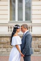 sessão de fotos de casamento no fundo do antigo prédio. o noivo observa sua noiva posando. fotografia de casamento rústica ou boho.