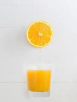 laranja pingando suco sobre um copo de suco de laranja foto