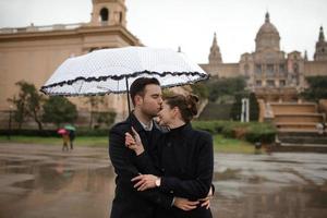 jovem lindo casal hispânico amoroso caminha sob um guarda-chuva durante a chuva. foto