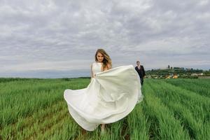 noivos em um campo de trigo. o casal se abraça durante o pôr do sol foto