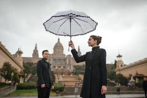 jovem lindo casal hispânico amoroso caminha sob um guarda-chuva durante a chuva. foto