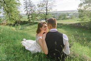 noivos em um campo de trigo. o casal se abraça durante o pôr do sol foto