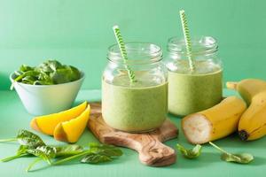 smoothie verde saudável com banana de manga espinafre em potes de vidro foto