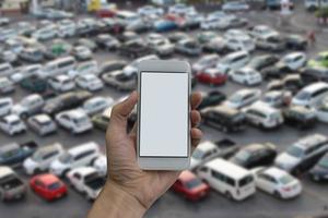 mão de homem segurando a tela vazia do telefone inteligente e estacionamento ao ar livre foto