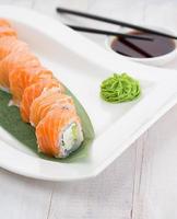 rolo de sushi de salmão em um prato branco com wasabi