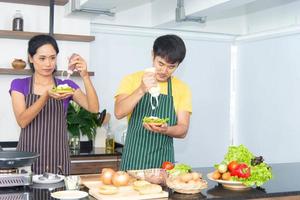 casal romântico e adorável asiático gosta e feliz cozinhando comida na cozinha foto