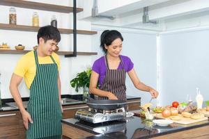 casal romântico e adorável asiático gosta e feliz cozinhando comida na cozinha foto
