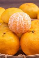 fresca, linda tangerina de cor laranja na peneira de bambu sobre a mesa de madeira escura. fruta sazonal e tradicional do ano novo lunar chinês, close-up. foto