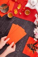 conceito de design do ano novo de janeiro lunar chinês - mulher segurando, dando envelopes vermelhos ang pow, hong bao por dinheiro da sorte, vista superior, postura plana, sobrecarga acima. a palavra 'chun' significa a chegada da primavera. foto