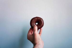 mão com um donut de chocolate foto