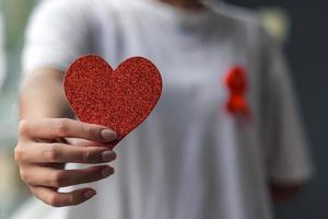 mão segurando o amor de coração vermelho em forma de campanha de câncer de mama foto