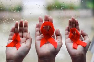 fita vermelha nas mãos para aids e fundo de campanha de câncer foto