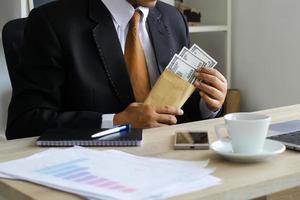 corrupção e suborno, empresário recebendo dinheiro em sua mesa de escritório foto