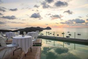 café aconchegante e romântico com mesa e cadeiras na cobertura com vista para o mar e pôr do sol foto