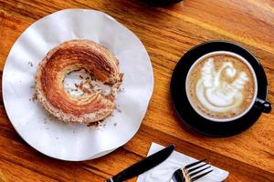 croissant e café com leite quente servido na mesa de madeira foto