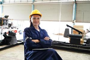 engenheiro industrial ou trabalhador usando um capacete em pé em uma fábrica industrial pesada. a manutenção procurando trabalhar em máquinas industriais e verificar a configuração do sistema de segurança na fábrica. foto