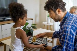 família amigável diversificada senta-se no sofá confortável na sala de estar aconchegante, pais multirraciais e seus filhos aproveitam o tempo juntos em casa foto