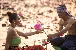 jovens mulheres asiáticas em trajes tradicionais no barco e flores de lótus rosa na lagoa foto