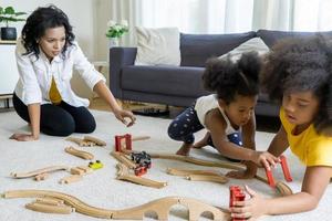 retrato de uma jovem família afro-americana feliz com crianças sentadas relaxando no sofá abraçando, sorrindo pais negros descansam no sofá abraçam crianças pré-escolares posando para foto em casa juntos