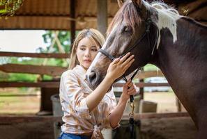 jovem e bonita com seu cavalo na luz do sol à noite. fotografia ao ar livre com garota modelo de moda. humor de estilo de vida foto