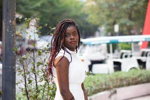 jovem mulher afro-americana de pele negra vestindo roupas casuais, de pé no fundo da cidade em positivo, sorrindo confiante. amor próprio e autocuidado foto