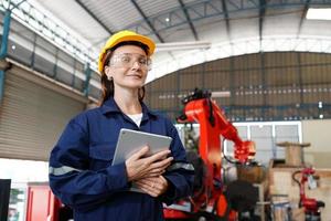 profissional jovem funcionária de fábrica industrial trabalhando com peça de máquina, verificando e testando equipamentos industriais e braços robóticos em grande fio de eletrônica elétrica e fábrica foto