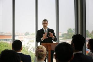 orador dando apresentação no salão. auditório ou sala de conferências. vista traseira de participantes não reconhecidos na audiência. evento de conferência científica, treinamento foto