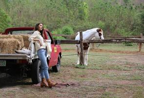 jovem e bonita com seu cavalo na luz do sol à noite. fotografia ao ar livre com garota modelo de moda. humor de estilo de vida foto