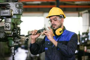 funcionário de fábrica industrial profissional trabalhando com peça de máquina, verificando e testando equipamentos industriais e braços robóticos em grande fábrica de plantas de fabricação de fios e cabos eletrônicos elétricos foto