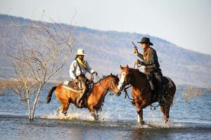 cowboy a cavalo contra um belo pôr do sol, cowboy e cavalo na primeira luz, montanha, rio e estilo de vida com fundo de luz natural foto