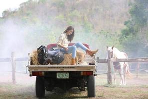 jovem e bonita com seu cavalo na luz do sol à noite. fotografia ao ar livre com garota modelo de moda. humor de estilo de vida foto