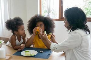 retrato de uma jovem família afro-americana feliz com crianças sentadas relaxando no sofá abraçando, sorrindo pais negros descansam no sofá abraçam crianças pré-escolares posando para foto em casa juntos