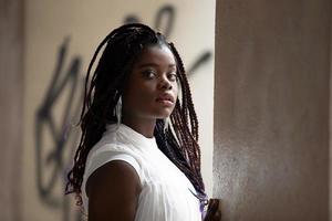 jovem mulher afro-americana de pele negra vestindo roupas casuais, de pé no fundo da cidade em positivo, sorrindo confiante. amor próprio e autocuidado foto