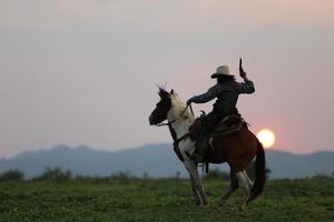 cowboy a cavalo contra um belo pôr do sol, cowboy e cavalo na primeira luz, montanha, rio e estilo de vida com fundo de luz natural foto