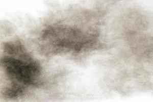 explosão de pólvora negra contra fundo branco. partículas de poeira preta espirrando. foto