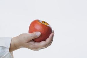 fechar a mão feminina madura segurando a maçã vermelha fresca no fundo branco foto
