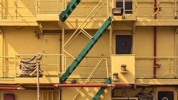 parte das escadas verdes para cima e para baixo com corrimão na popa do velho grande navio de metal amarelo foto