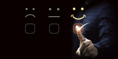 empresário tocando a tela de toque virtual para selecionar o botão de emoção do rosto sorridente para a melhor avaliação, conceito de satisfação do cliente. foto