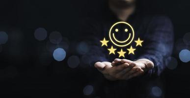 empresário segurando o ícone de sorriso para a melhor avaliação, conceito de satisfação do cliente. foto