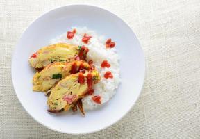 omelete fatiado com tofu macio, vara de caranguejo e cebolinha com arroz no prato foto