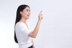 mulher asiática com cabelos longos pretos veste camisa branca e aponta a mão para apresentar algo sobre o fundo branco. foto